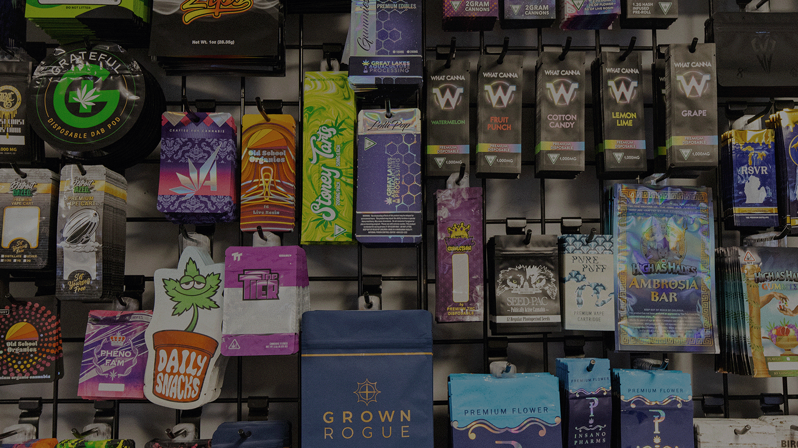 Display of various cannabis product baggies with colorful packaging hanging on a wall.